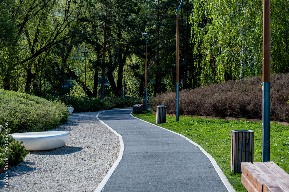 A winding asphalt pedestrian path in the park on a spring day. A winding asphalt pedestrian path in the park on a spring day.