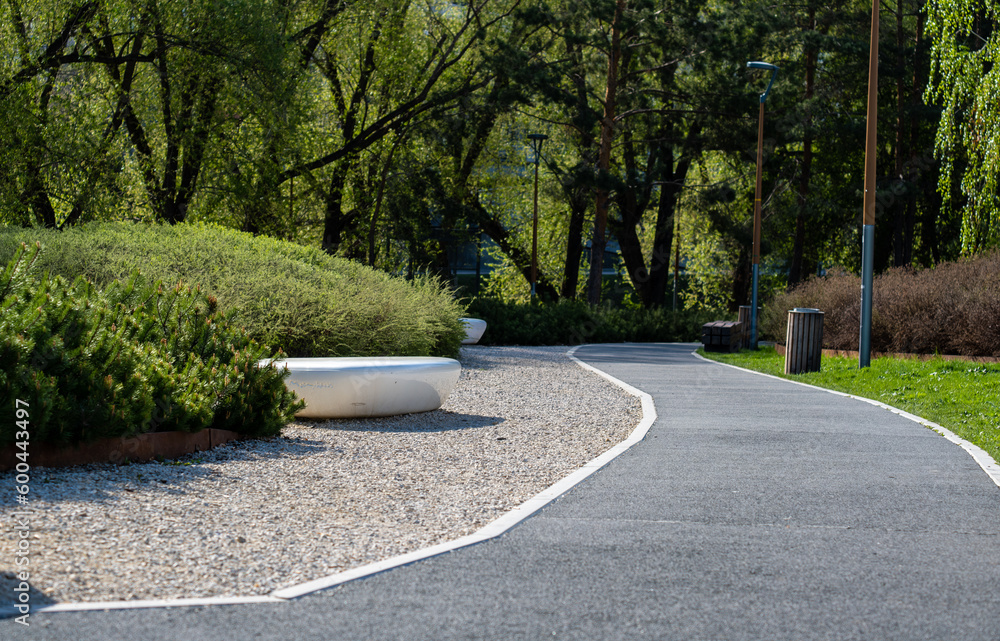 A winding asphalt pedestrian path in the park on a spring day. A winding asphalt pedestrian path in the park on a spring day.