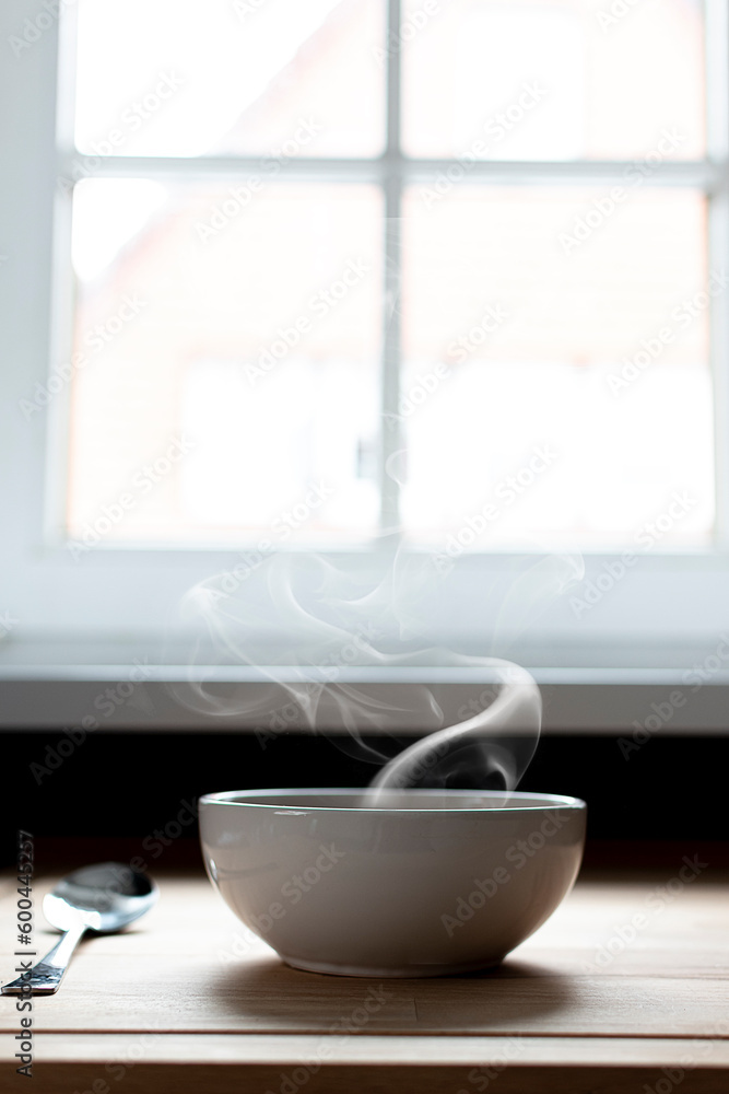 Bowl of soup next to a window. Steam of hot soup. Warm food Bowl of soup next to a window. Steam of hot soup. Warm food