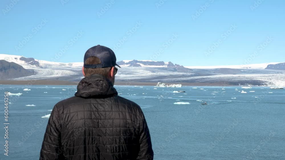 Man looking at Jokulsarlon glacier Lagoon, Iceland. Stunning icebergs floating in lagoon, powerful message of climate change in Iceland. Perfect light and weather. High quality 4k footage. Man looking at Jokulsarlon glacier Lagoon, Iceland. Stunning icebergs floating in lagoon, powerful message of climate change in Iceland. Perfect light and weather. High quality 4k footage.