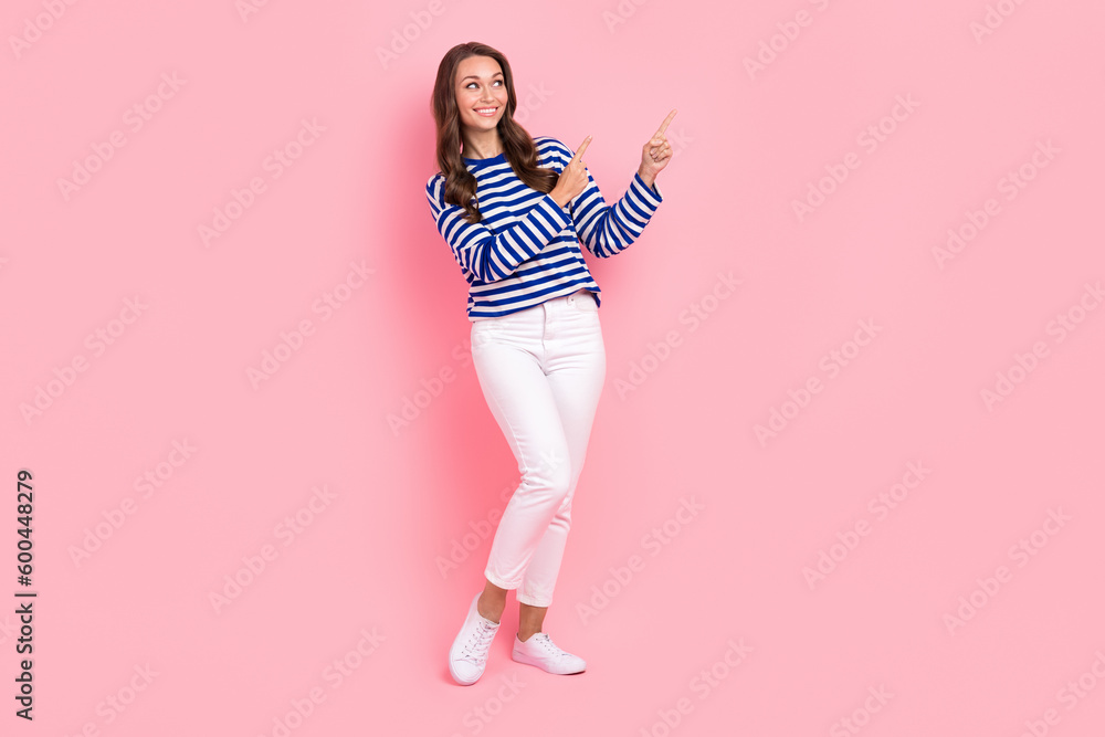 Full size photo of adorable lovely positive girl wear striped clothes directing look at sale empty space isolated on pink color background Full size photo of adorable lovely positive girl wear striped clothes directing look at sale empty space isolated on pink color background