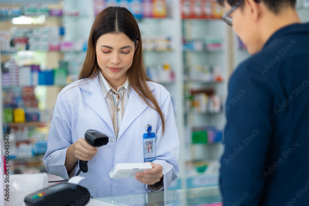 Asian female pharmacist holding bar code reader scanning pills box at the pharmacy. Shelves with drug and Health Care product