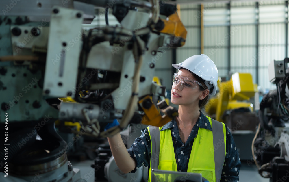 A female engineer installs a program on a robotics arm in a robot warehouse. And test the operation before sending the machine to the customer. A female engineer installs a program on a robotics arm in a robot warehouse. And test the operation before sending the machine to the customer.