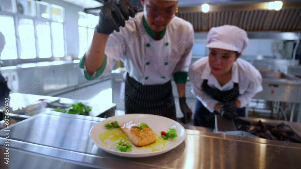 Closeup hands of chef man cooking salmon steak and decoration on plate with professional in kitchen at restaurant, food and garnish for serving, food japan, culinary and recipe with delicious. Closeup hands of chef man cooking salmon steak and decoration on plate with professional in kitchen at restaurant, food and garnish for serving, food japan, culinary and recipe with delicious.