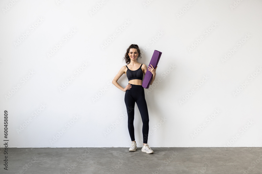 Woman holding a yoga mat in a white background
