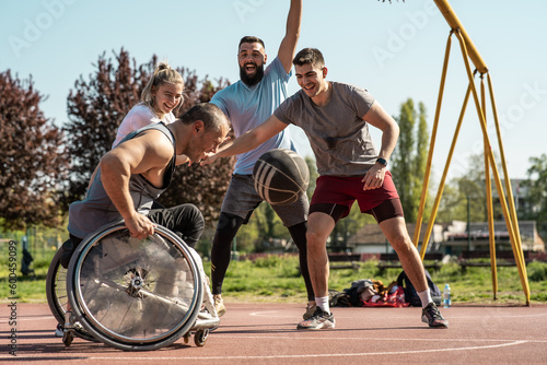 A physically challenged man in a wheelchair fearlessly engages in a spirited game of basketball with his supportive friends, breaking barriers and proving that passion and teamwork know no bounds.