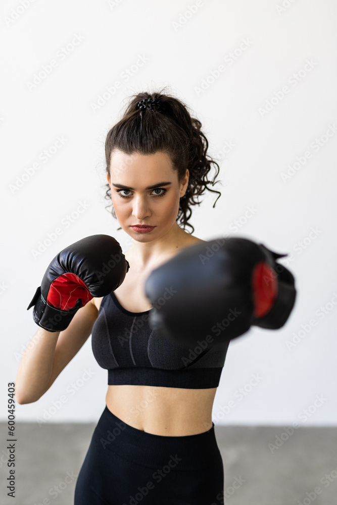 Portrait of beautiful young woman in sportswear with red boxing gloves pose show punch while fitness training and exercise at home. Female workout fit for healthcare and body weight control.