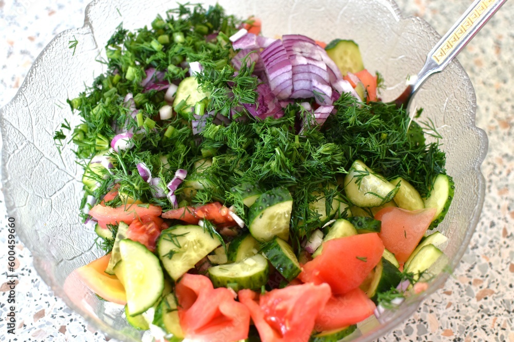 fresh salad of cucumbers, tomatoes and dill in a glass bowl