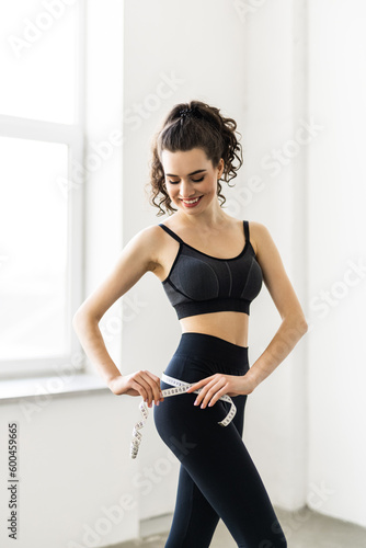 diet, sport and heath concept - beautiful sporty woman with measuring tape at home © F8  \ Suport Ukraine