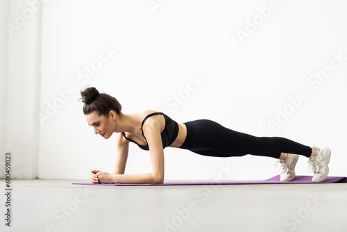 Fit woman doing plank exercise, workout at home