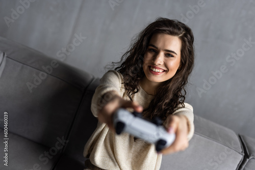 Young woman play games with console sit on couch