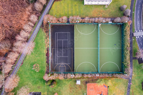 Sport ground in a college or university student camp. Aerial top down view on basketball, tennis and mini soccer or football court and walking path.