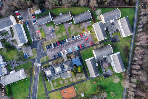 College or university camp site with small houses and green grass area, road and parking lot. Aerial top down view. High density residential area.