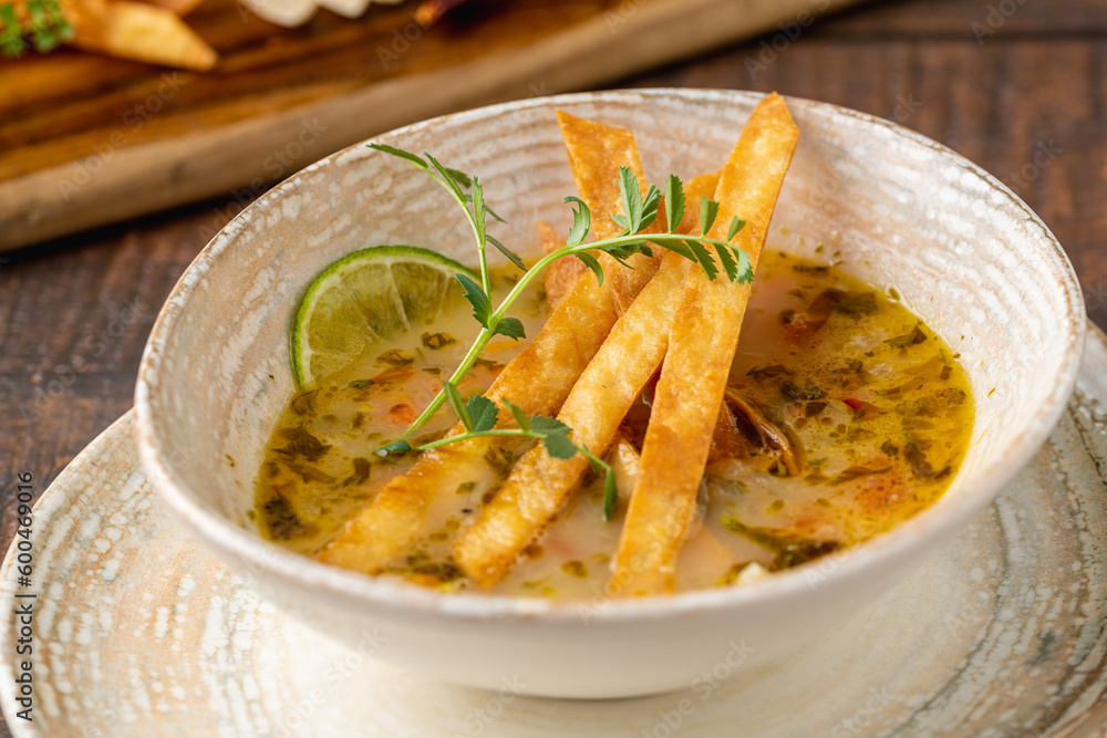 Bowl of tasty Sopa de Lima soup on wooden table