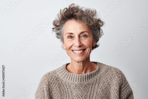 Portrait of a smiling senior woman in sweater looking at camera over white background