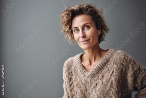 Portrait of a beautiful middle-aged woman in a sweater on a gray background