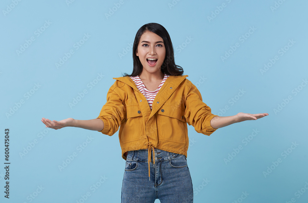 Happy beautiful Asian woman smiling with open hand gesture of welcome isolated on blue background. Happy beautiful Asian woman smiling with open hand gesture of welcome isolated on blue background.