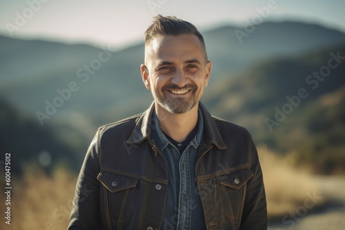 Portrait of a handsome man with a beard in a leather jacket in the mountains