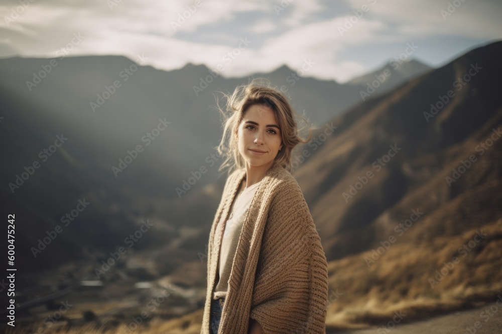 Young woman with long blond hair in beige sweater on the background of mountains