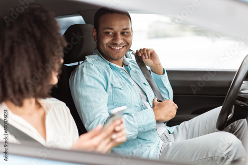 Man Fastening Seat Belt Smiling To Passenger Lady In Automobile