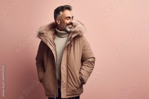 smiling middle aged man in winter jacket looking away isolated on pink