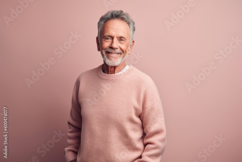 Portrait of a smiling senior man in a pink sweater on a pink background