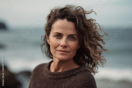 Portrait of mature woman with curly hair looking at camera on beach
