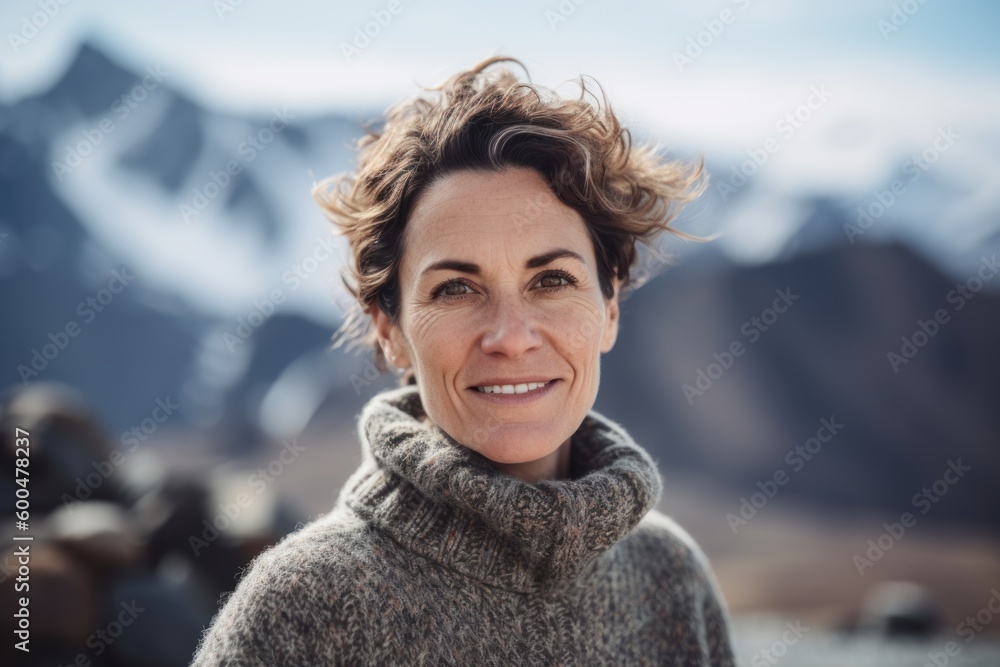 Portrait of smiling mature woman in sweater and scarf against snowy mountains Portrait of smiling mature woman in sweater and scarf against snowy mountains
