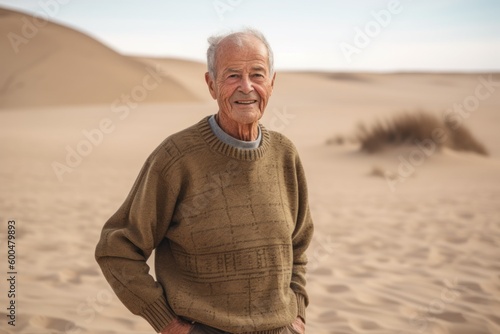 Lifestyle portrait photography of a pleased man in his 80s wearing a cozy sweater against a sand dune background. Generative AI