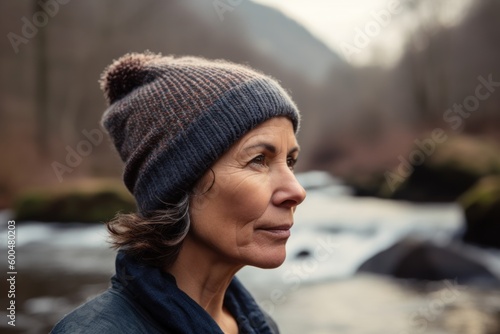 Portrait of a middle-aged woman in a knitted hat on the background of a river © Robert MEYNER