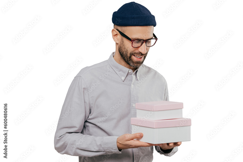 Φωτογραφία Indoor shot of handsome unshaven man with brislte holds two boxes, happy to recieve present from friend on birthday, wears festive clothes, models against grey background