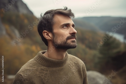 Portrait of a handsome young man in a sweater on a background of mountains.