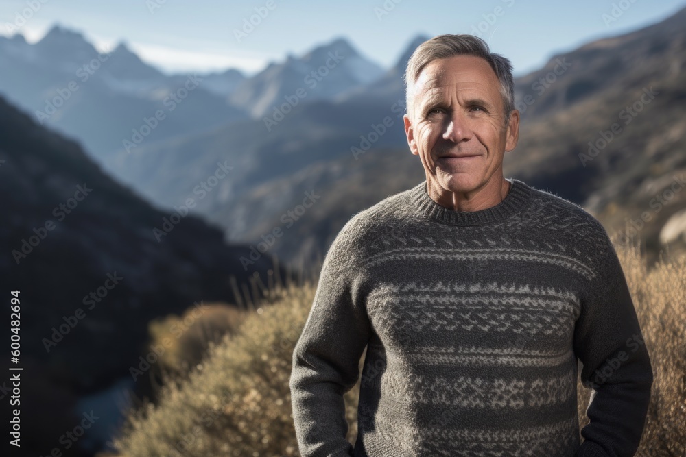 Portrait of a handsome mature man standing in the mountains looking at camera