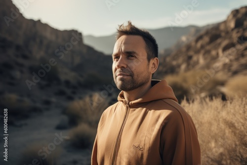 Environmental portrait photography of a satisfied man in his 30s wearing a comfortable tracksuit against a mountain valley or canyon background. Generative AI