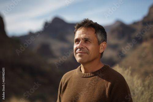 Handsome middle-aged Hispanic man in a brown sweater in the mountains