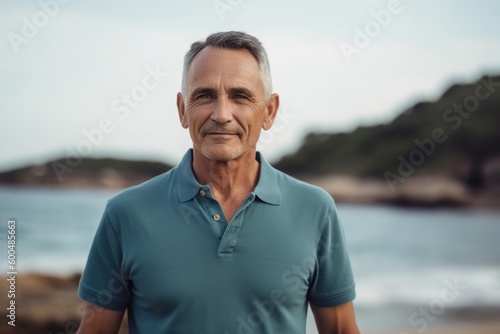 Portrait of senior man looking at camera while standing on the beach