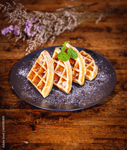 Belgian waffles with chocolate sauce isolated on wood background