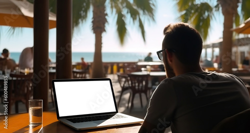 Wallpaper Mural Young man using laptop with a cut out screen at sea resort. Remote work and business in palm paradise. Online purchase of air tickets and hotels. Copy space. Based on Generative AI Torontodigital.ca