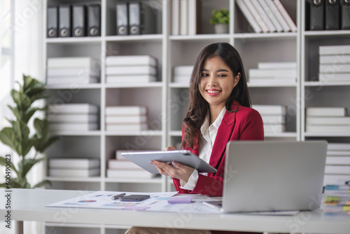 Young woman working on a laptop in the office. Asian businesswoman sitting at her workplace in the office. Beautiful Freelancer Woman working online at her home.