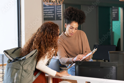 Young woman checks in at front desk, reception, hotel, college library admission photo