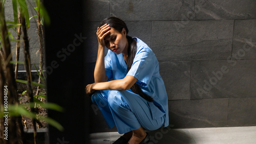 Hight contrast and drama concept. tired exhausted nurse or doctor woman sitting outside hospital. healthcare and medicine concept © NVB Stocker