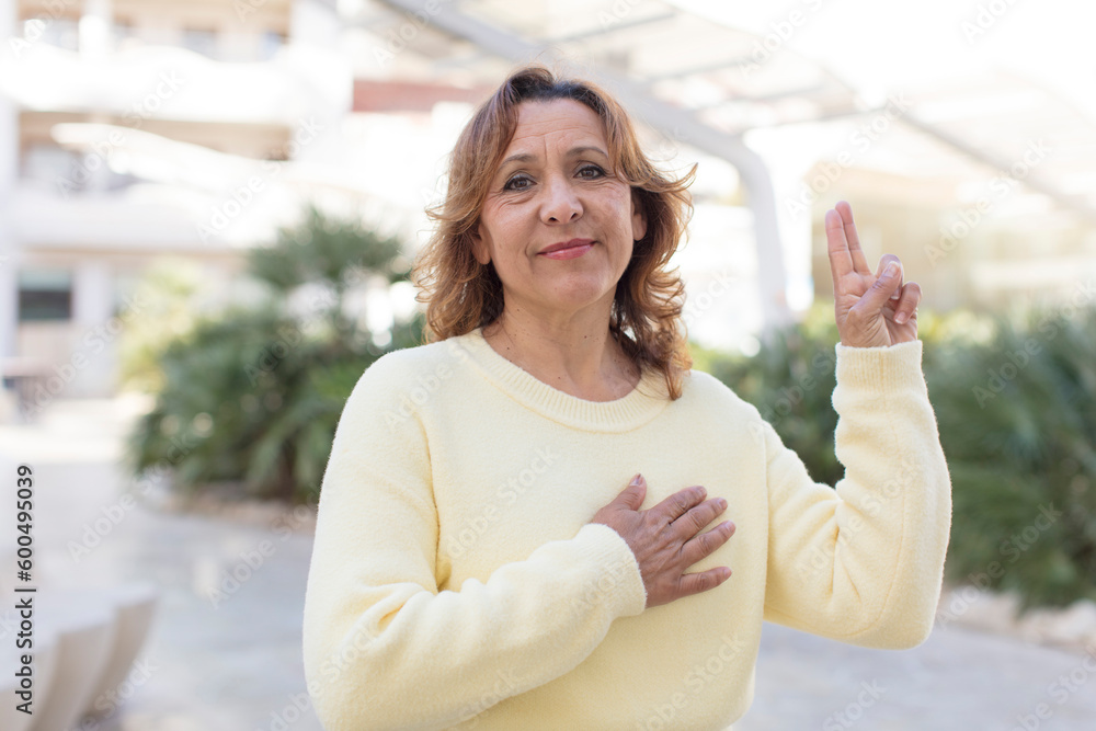 Fototapeta premium middle age woman looking happy, confident and trustworthy, smiling and showing victory sign, with a positive attitude