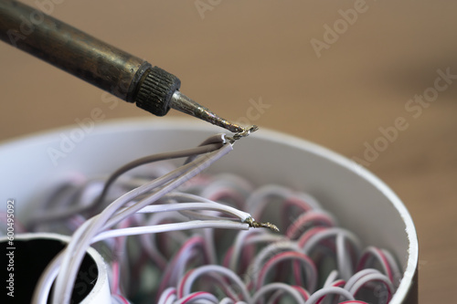 The soldering iron solders the twisted wires with tin solder.Soldering of wires.Reliable contact.