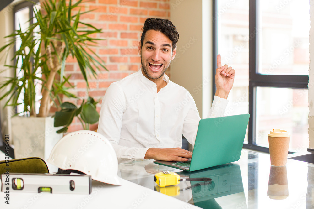 young hispanic man feeling like a happy and excited genius after realizing an idea, cheerfully raising finger, eureka!. architect concept young hispanic man feeling like a happy and excited genius after realizing an idea, cheerfully raising finger, eureka!. architect concept
