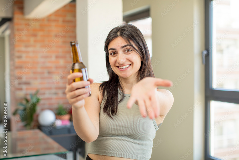 young woman smiling happily and offering or showing a concept. beer bottle young woman smiling happily and offering or showing a concept. beer bottle