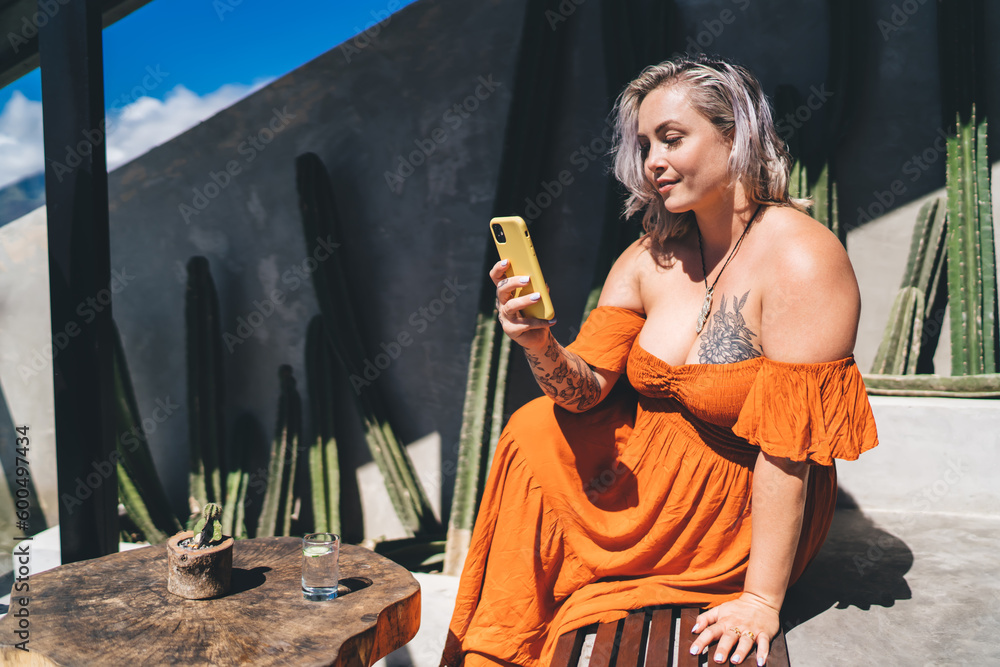 Obraz premium Young woman using smartphone while sitting in street cafe