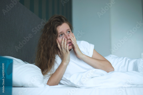 Sad upset depressed young woman suffer in bed in bedroom because of insomnia, tired girl with headache or hangover 