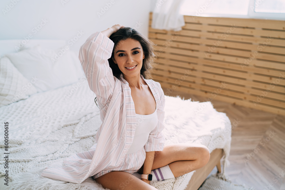 Smiling ethnic woman looking at camera while resting on bed Smiling ethnic woman looking at camera while resting on bed