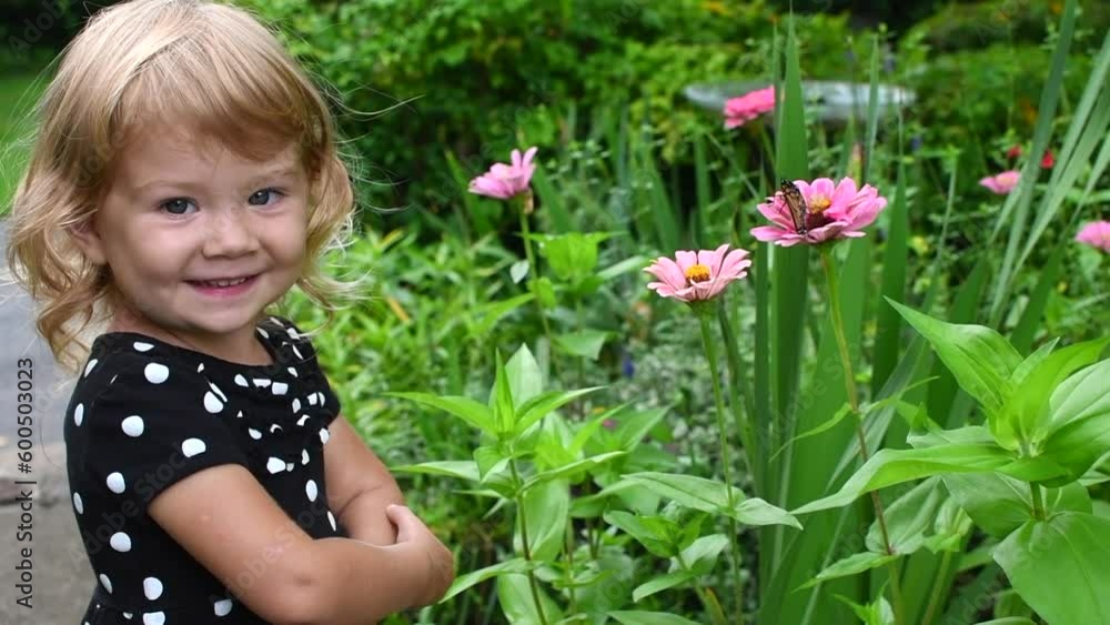 Cute Caucasian toddler little girl is playing with Monarch Butterfly. Kids exploring outdoors. Child education. Cute Caucasian toddler little girl is playing with Monarch Butterfly. Kids exploring outdoors. Child education.