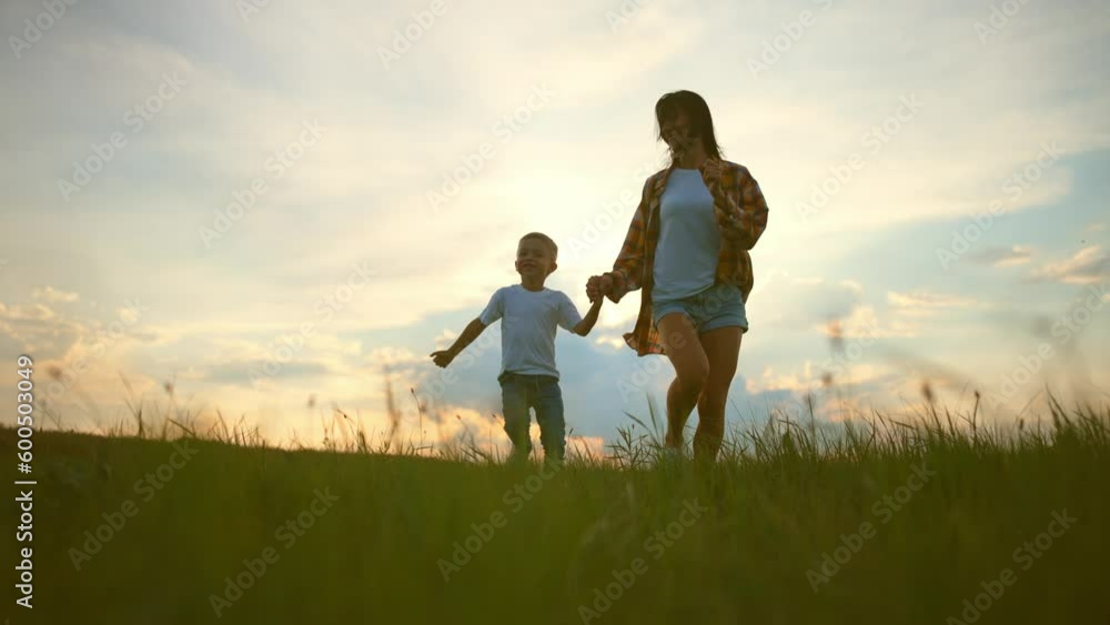 Silhouette mom and his son are running to the sunset. Silhouette of happy family. Mother and son in park. Silhouette mom and his son are running to the sunset. Silhouette of happy family. Mother and son in park.